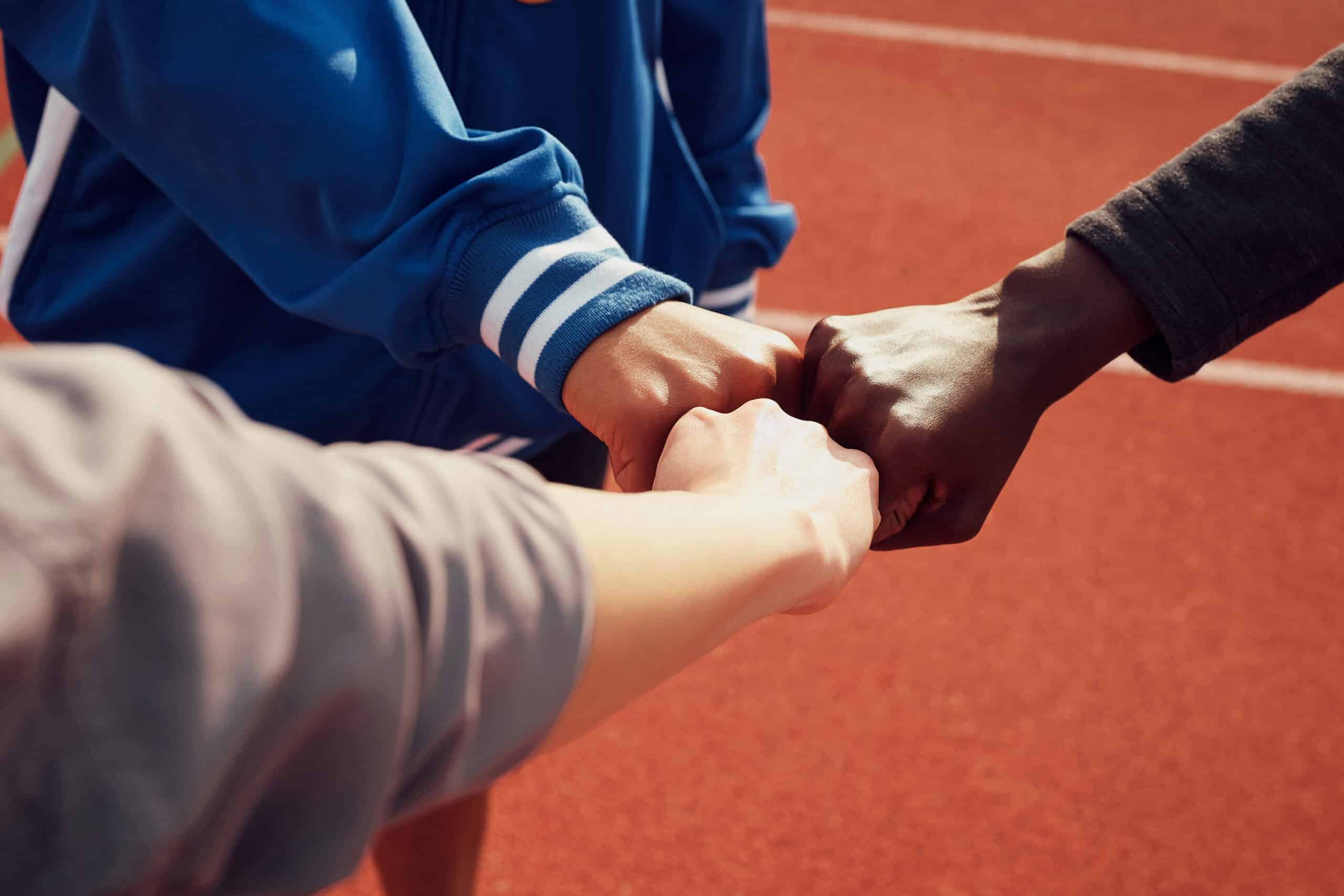 Three fists coming together and the forearms of three people.