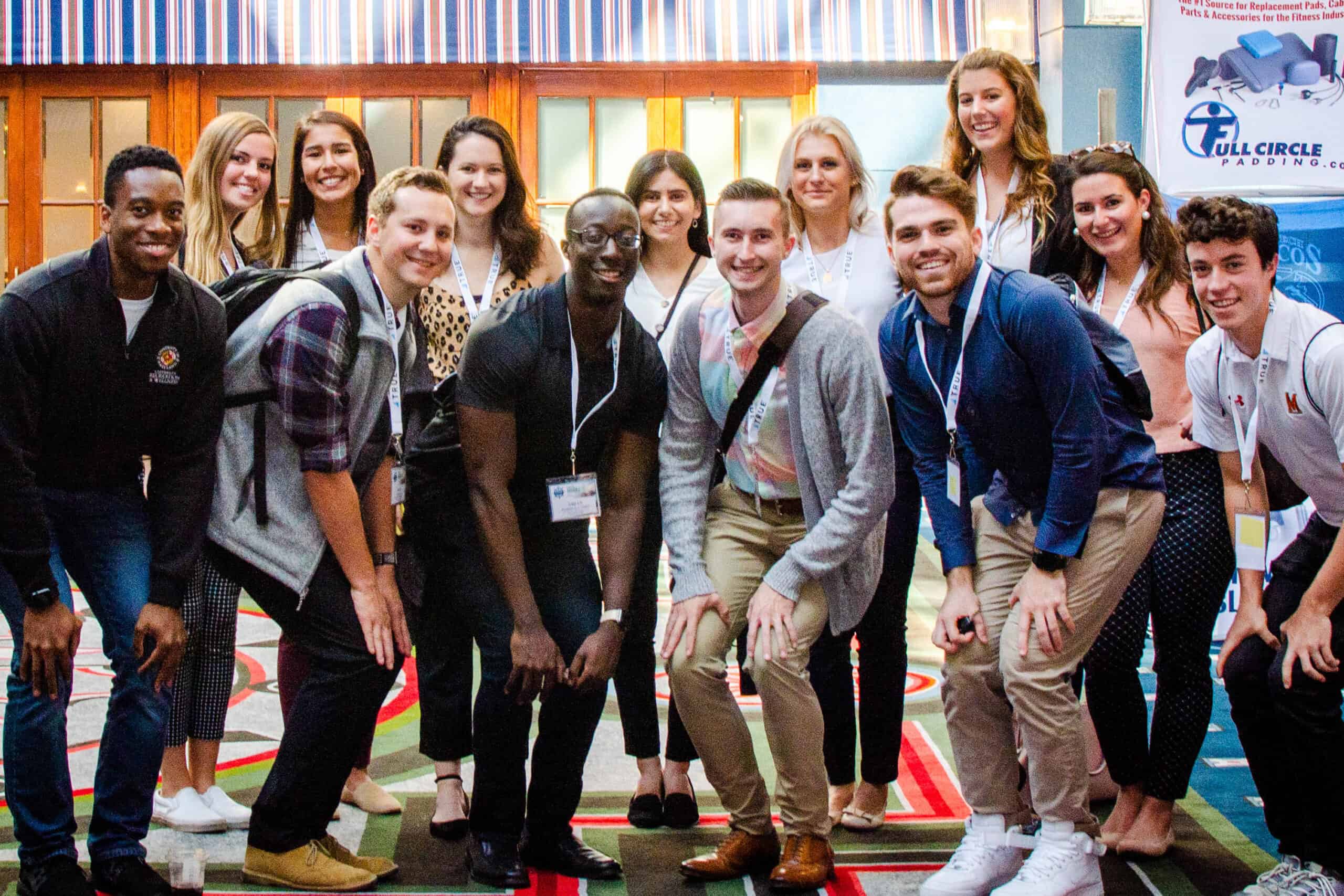A group of students and young professionals smiling and posing together at an event.