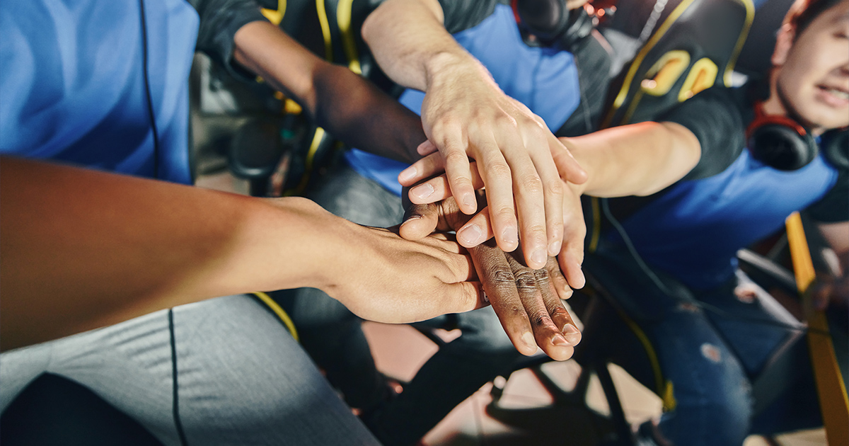 Esports players with their hands in for a cheer