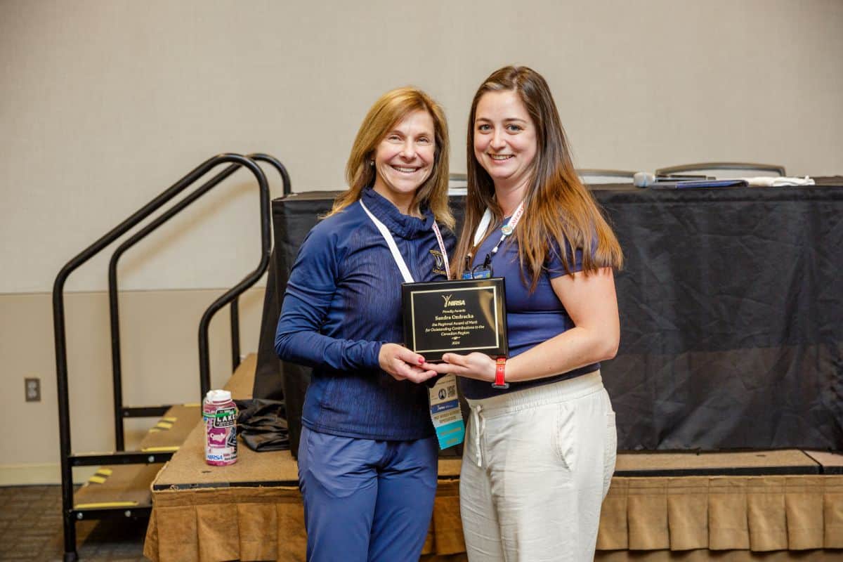 Two people smiling and posing for a picture holding a plaque.