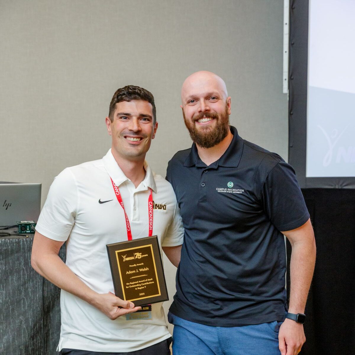 Two people smiling and posing for a picture holding a plaque.