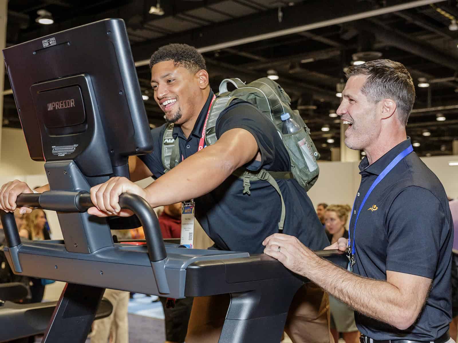 A person at the gym on a workout machine with his trainer