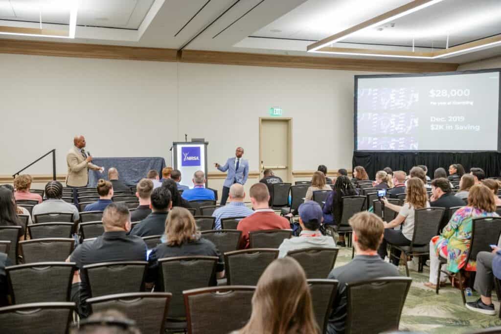 Two individuals presenting to a room full of people