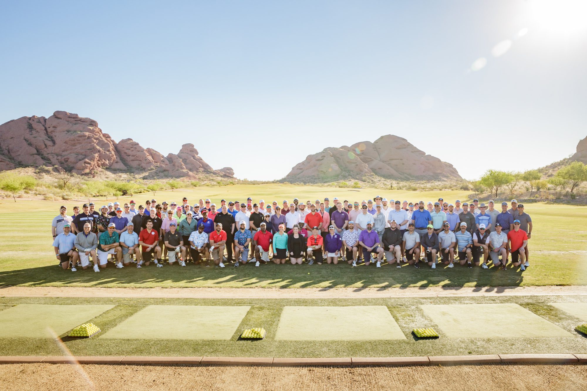 Large group of people standing on gold course on a sunny day